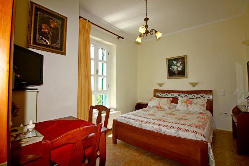 a bedroom with a bed and a desk and a television at Artemis Traditional Hotel in Myrina