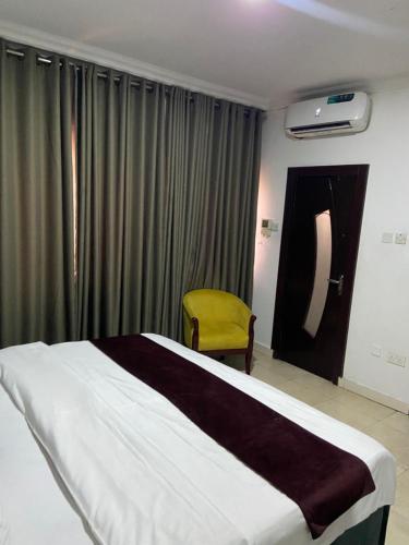 a bedroom with a large bed and a yellow chair at Crystal homes 1 in Lekki