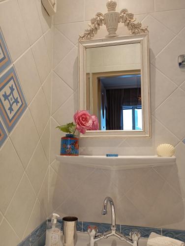 a bathroom sink with a mirror and a flower on a shelf at Casa da Sogno Elegant Studio in Nafpaktos