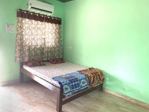 a small bed in a room with a green wall at Bachhav Farm House in Katrab