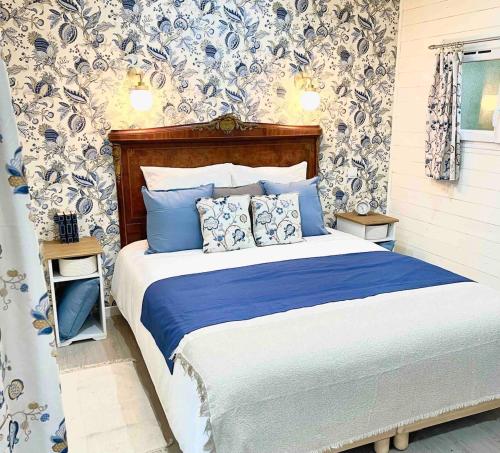 a bed with blue and white pillows in a bedroom at La roulotte du Manoir 1900 in La Ferté-Gaucher