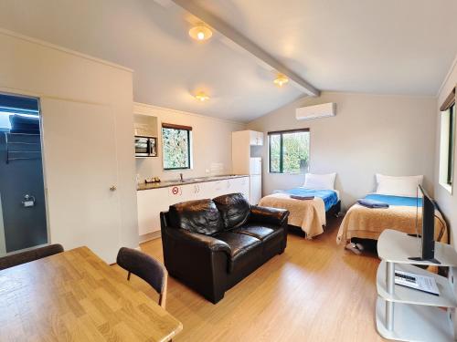 a living room with a couch and a bed at Parakai Geothermal Motel in Parakai