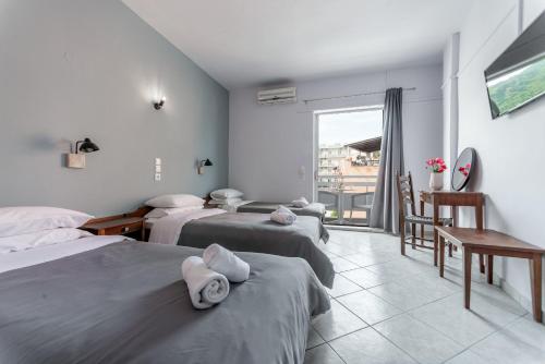 a hotel room with three beds and a balcony at Blue Sea Benitses in Benitses