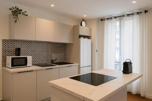 une cuisine avec des armoires blanches et un réfrigérateur blanc dans l'établissement Belle Epoque Bagtinolles, à Paris