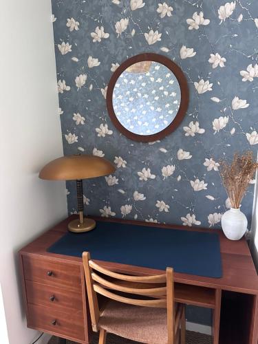 a desk with a mirror on a wall with flowers at L'échappée belle in Bessancourt