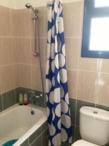 a bathroom with a blue and white shower curtain next to a toilet at paphos pool view gem - cozy 1 bed Apartment in Paphos