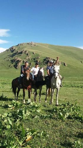 a group of people riding horses in a field at "Doskulu travel" hostel in Kyzart