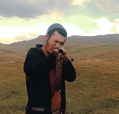 a man singing into a microphone in a field at "Doskulu travel" hostel in Kyzart