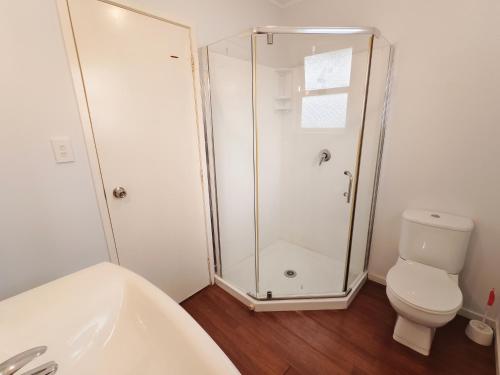 a bathroom with a shower and a toilet at Parakai Geothermal Motel in Parakai