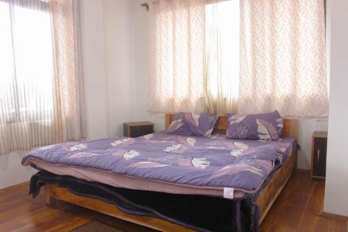 ダージリンにあるchattrapurna homestayのベッドルーム1室(紫のシーツが敷かれたベッド1台、窓2つ付)
