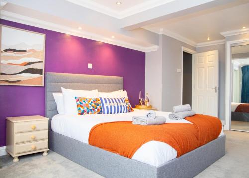 a bedroom with a large bed with an orange blanket at Stylish and Spacious 3-Bed House Free Parking in Ipswich