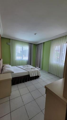 a bedroom with a bed and two windows at Kara Family Apart in Kemer