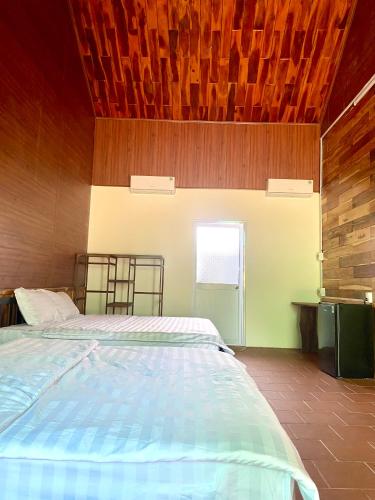a bedroom with a bed and a wooden ceiling at An Bình Home in Kon Rung (1)