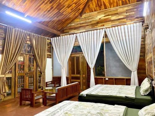 a bedroom with two beds and two windows at An Bình Home in Kon Rung (1)