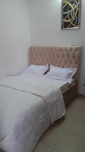 a large white bed with white sheets and pillows at Apparemment meublé bastos in Yaoundé
