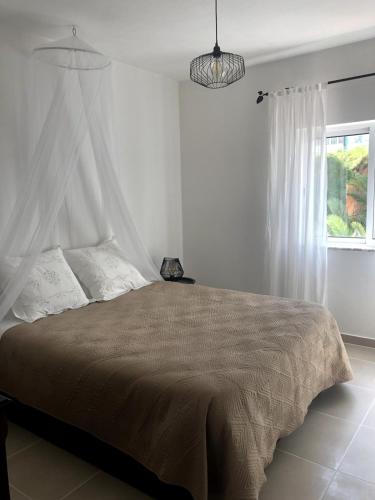 a white bedroom with a large bed with a canopy at Apt H - Beach Village in Olhos de Água