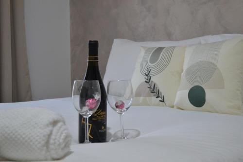 a bottle of wine and two glasses on a bed at Casa Rolland in Acilia