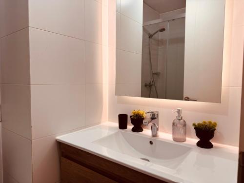 une salle de bain blanche avec un lavabo et un miroir dans l'établissement Edificio Claro Solar - Moderno Apartamento Centro Temuco 2D2B Parking, à Temuco