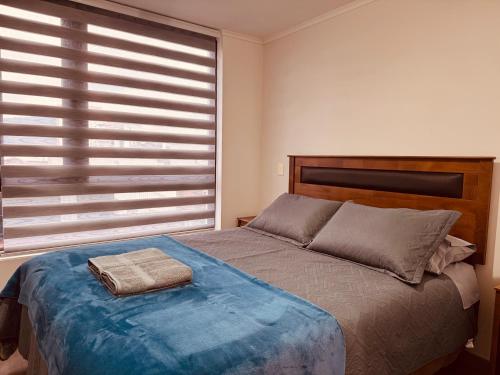 une chambre avec un lit avec une couverture bleue et une fenêtre dans l'établissement Edificio Claro Solar - Moderno Apartamento Centro Temuco 2D2B Parking, à Temuco