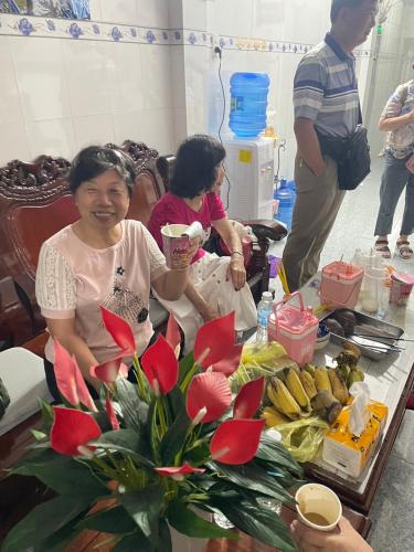 a woman sitting in front of a table with flowers at Nhà Nghĩ Hồng Hải in Ap Vi Binh