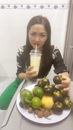 a woman sitting at a table with a plate of fruit at Nhà Nghĩ Hồng Hải in Ap Vi Binh