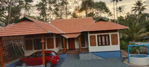 a small house with a red car in front of it at Island Retreat Homestay in Munroe Island