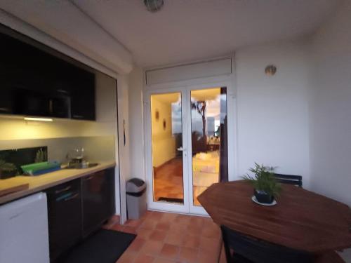 a kitchen with a table and a sliding glass door at L'Oasis de Tartane in La Trinité