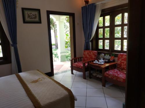 une chambre avec un lit, une table et des chaises dans l'établissement Gold Rooster Resort, à Phan Rang