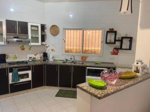 a kitchen with black cabinets and a green bowl on a counter at Maison El Omrane 2 in Bin Rhilouf
