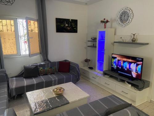 a living room with a couch and a flat screen tv at Maison El Omrane 2 in Milletville