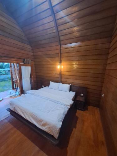 a bedroom with a bed in a wooden wall at Rinjani Koceng Bungalow in Tetebatu