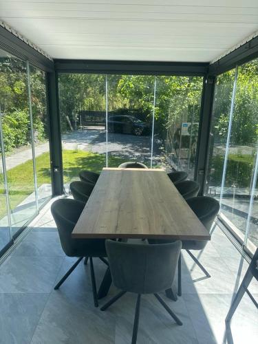 a wooden table and chairs in a room with windows at Szigligeti Strand Apartman in Szigliget