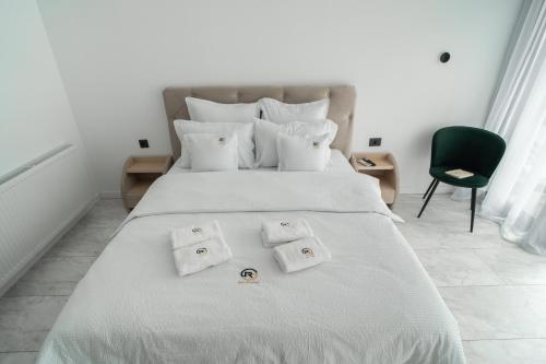 a white bed with three towels on top of it at Gold Residence in Ocna-Mureşului