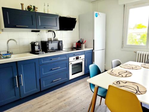 une cuisine avec des placards bleus et une table avec des chaises dans l'établissement La Casa Jungle, 3 bedrooms, Angers, à Angers