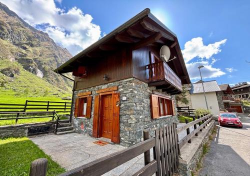 a small house with a wooden door and a fence at Chalet Caldo & Accogliente a Cheggio "Obrigado House" in Alpe Cheggio