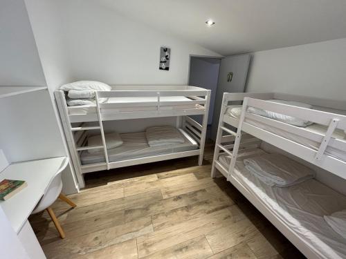 a room with three bunk beds and a wooden floor at Villa avec Piscine chauffée, a 5mn de la plage in Sainte-Marie-de-Ré
