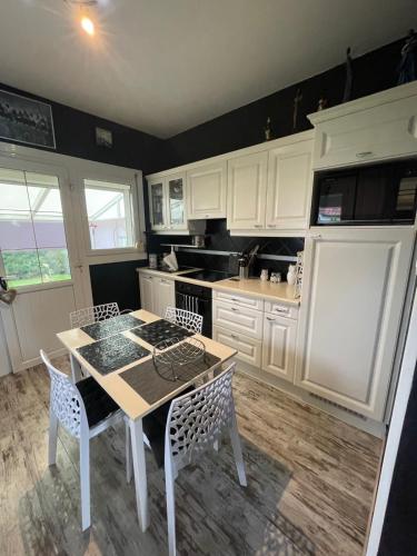 une cuisine avec des armoires blanches et une table et des chaises dans l'établissement Charmante maison 3 chambres, à Cucq