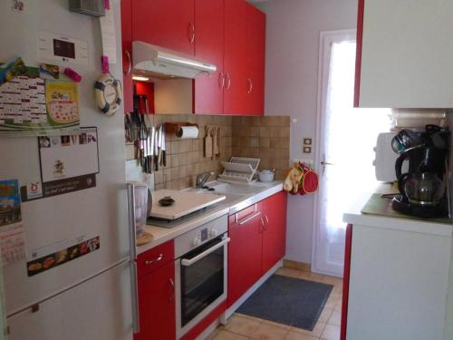 une cuisine avec des armoires rouges et un réfrigérateur blanc dans l'établissement Maison 3 pièces, 5 couchages à Landevieille, terrasse, Wi-Fi - FR-1-224A-8, à Landevieille