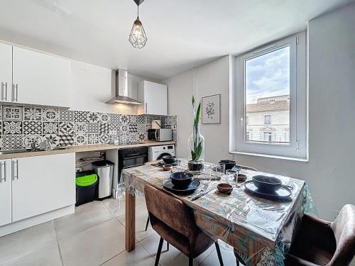une cuisine avec une table et des chaises ainsi qu'une fenêtre dans l'établissement Le Bohja - Charming apartment near Les Halles, à Narbonne