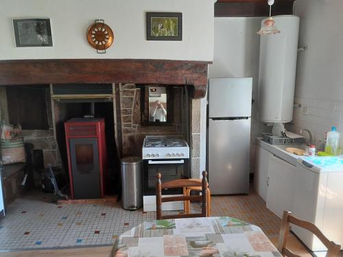 Il comprend une cuisine équipée d'un réfrigérateur ancien et d'une cuisinière. dans l'établissement Maison de campagne, à Sérandon