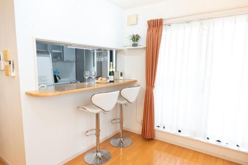 a kitchen with a bar with two white stools at 4 卧室 - 3 浴室 - 3 卫生间 - 100 平方 新装 别墅 - 新宿 4 分钟 - Sakura House in Tokyo