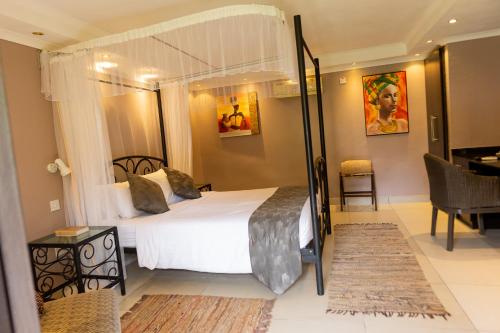 a bedroom with a canopy bed and a desk at Casa Mia Lodge & Restaurant in Blantyre