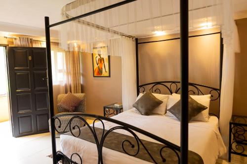 a bedroom with a black bed with white sheets and pillows at Casa Mia Lodge & Restaurant in Blantyre
