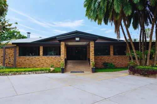 a brick house with palm trees in front of it at Casa Mia Lodge & Restaurant in Blantyre