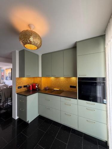 Il comprend une cuisine avec des placards blancs et du carrelage noir au sol. dans l'établissement Appartement F3 Vue mer Sainte-Maxime, à Sainte-Maxime