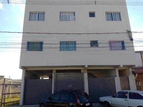 two cars parked in front of a white house at Bem Estar4 in Aparecida