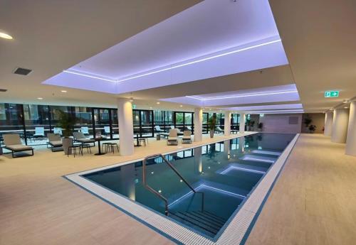 a large swimming pool in a building with tables and chairs at Brand new 1B apartment in Woden near Hospital Westfield and pool gym in Phillip
