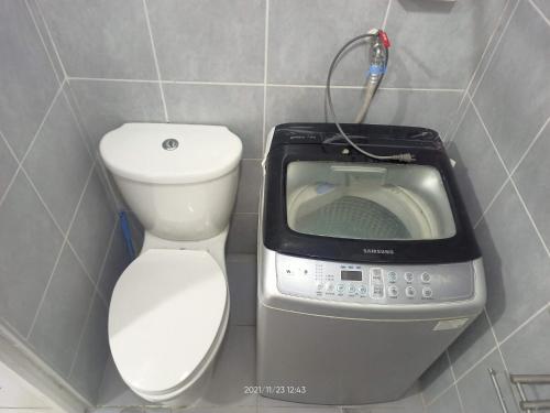 a toilet and a washing machine in a bathroom at Sea Residences Mall of Asia Viann in Manila