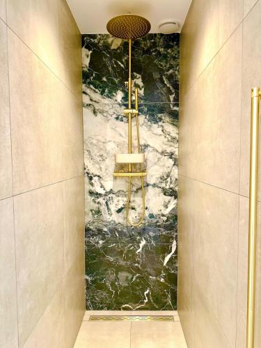 a shower in a bathroom with a marble wall at Wilde Gist Guesthouse in Sint Agatha