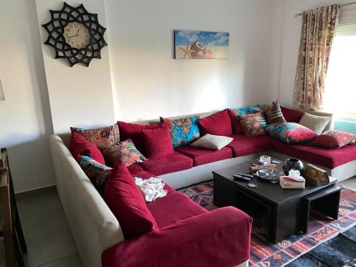 a living room with a red couch and a table at Amwaj ground apartment in El Alamein